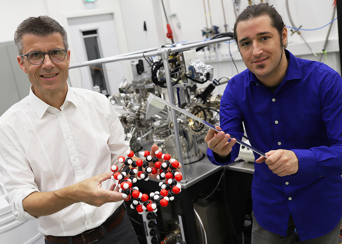 Photo taken in the physics lab with two scientists: Professor Dr. Dario Anselmetti from Bielefeld University with a spherical model of a cyclodextrin molecule, PhD student Niklas Biere with the model of a force sensor.