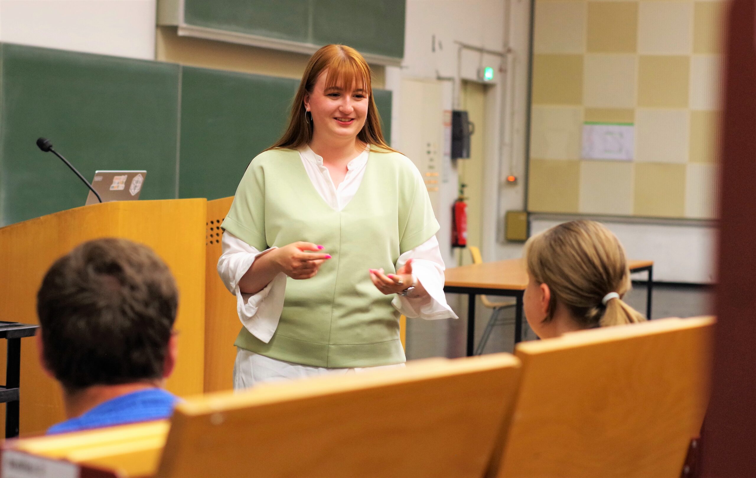 Lea Hildermeier spricht zu zwei Mitgliedern des LiLiGoesMental-Teams in einem Hörsaal der Universität.
