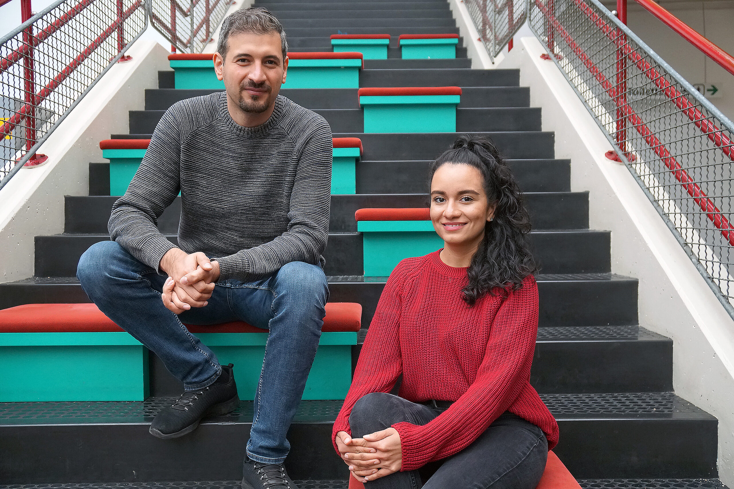 Mustafa Braun und Marcela Feijoo Gomez sitzen auf einer Treppe.