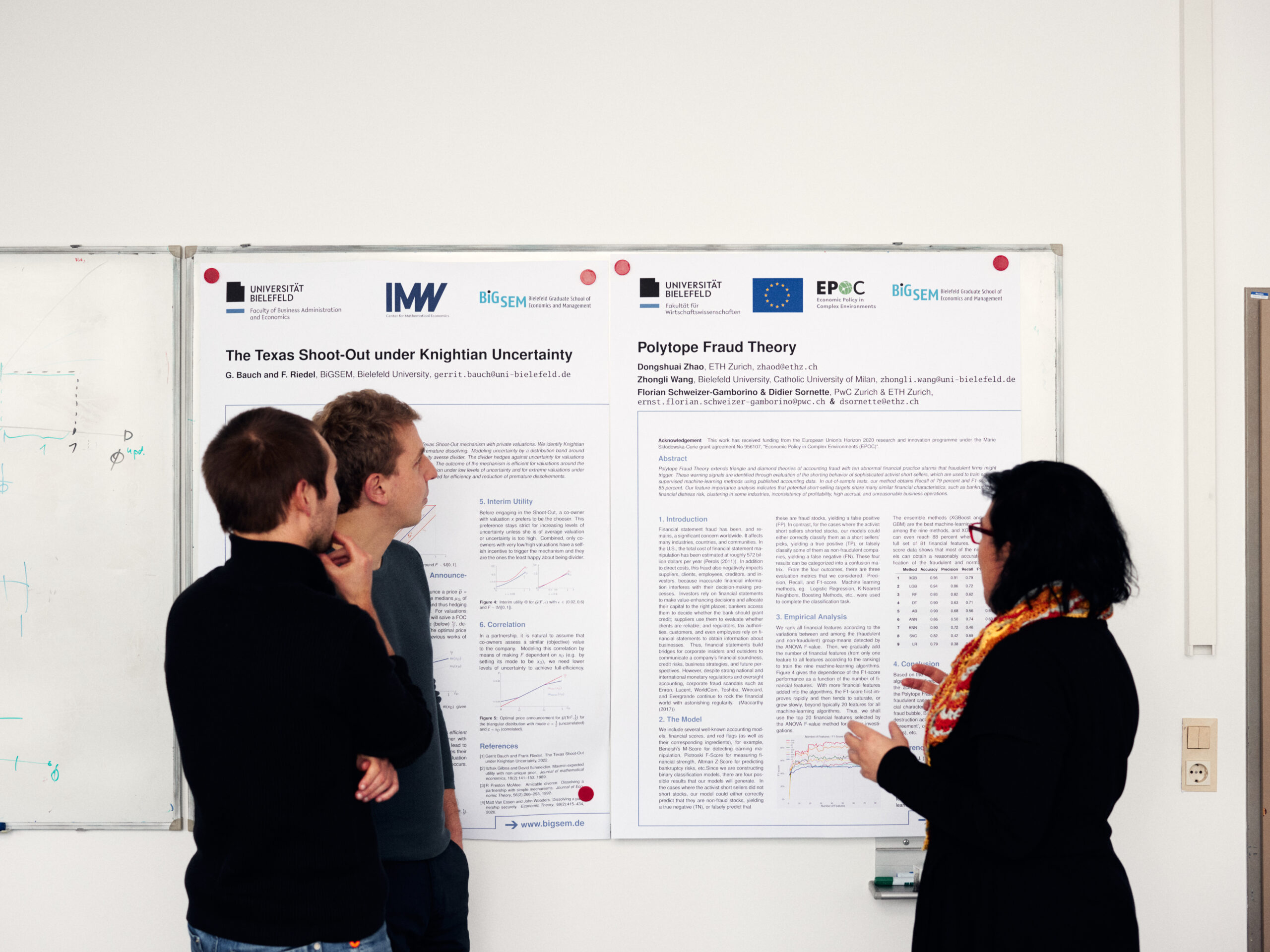 Drei junge Forscher*innen diskutieren vor zwei Postern ihre Arbeit.