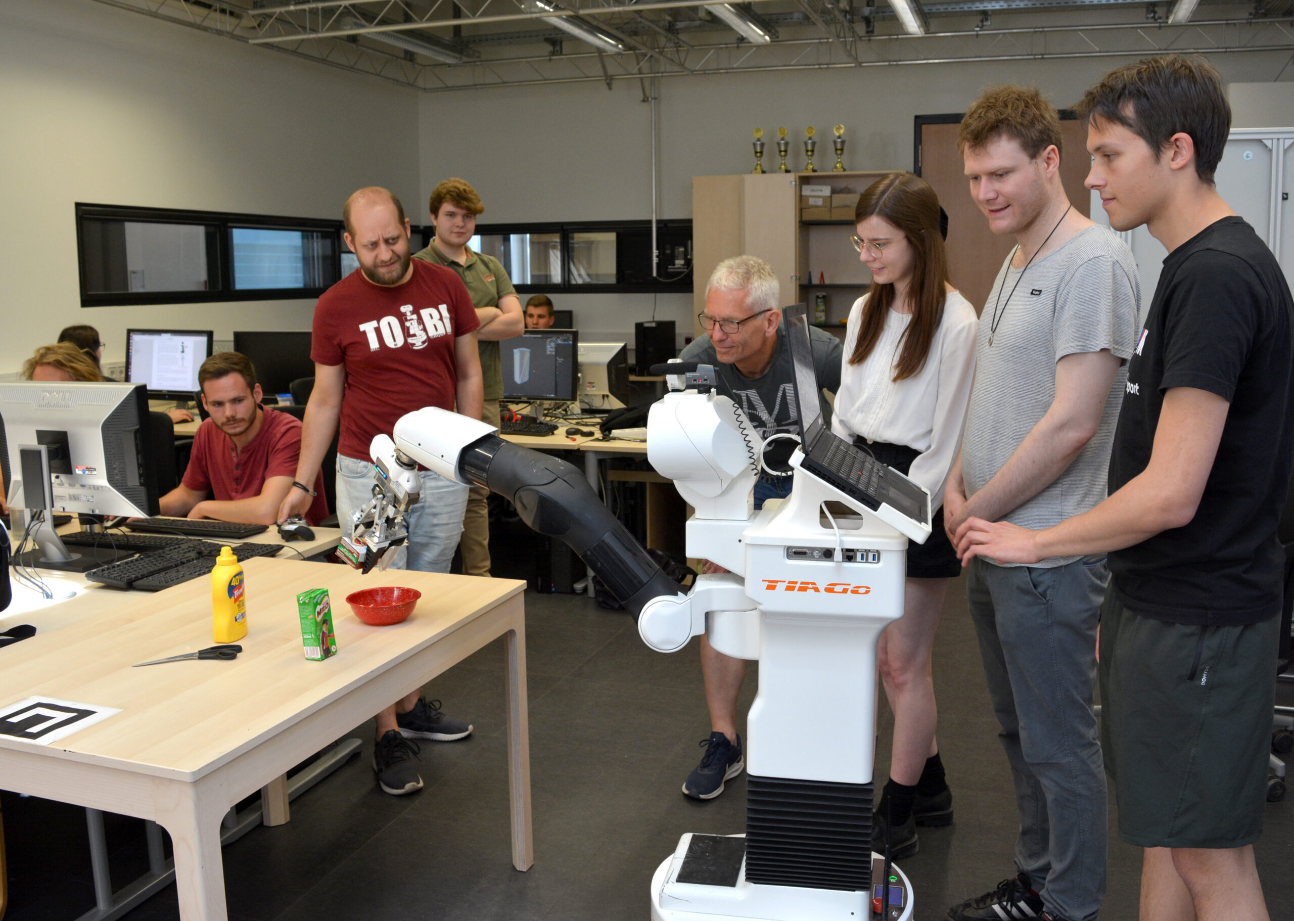 Wissenschaftler*innen und Studierende bei der Arbeit mit einem Service-Roboter