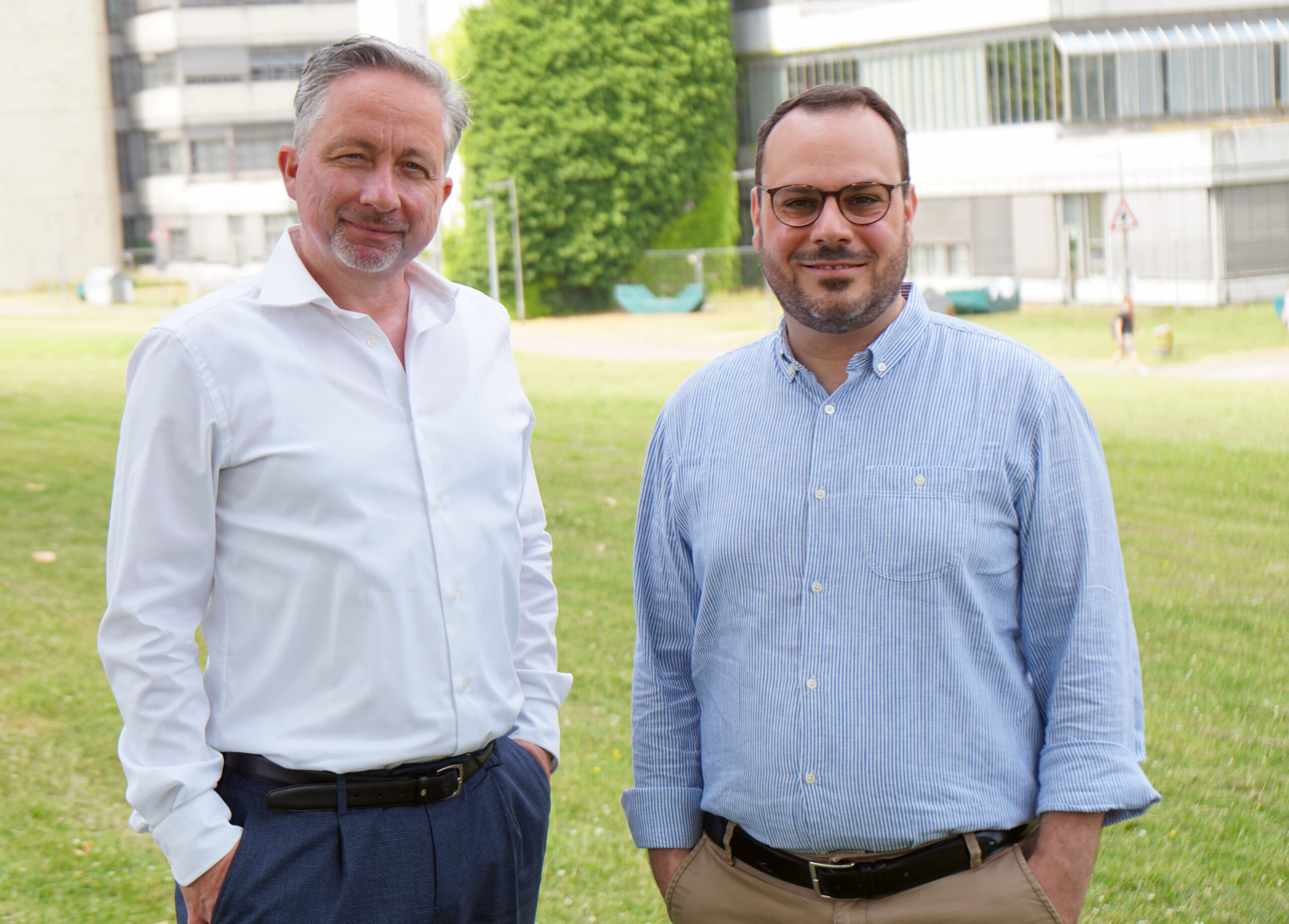 Prof. Dr. Frank Riedel und Prof. Dr. Giorgio Ferrari vor einem Gebäude der Universität Bielefeld.