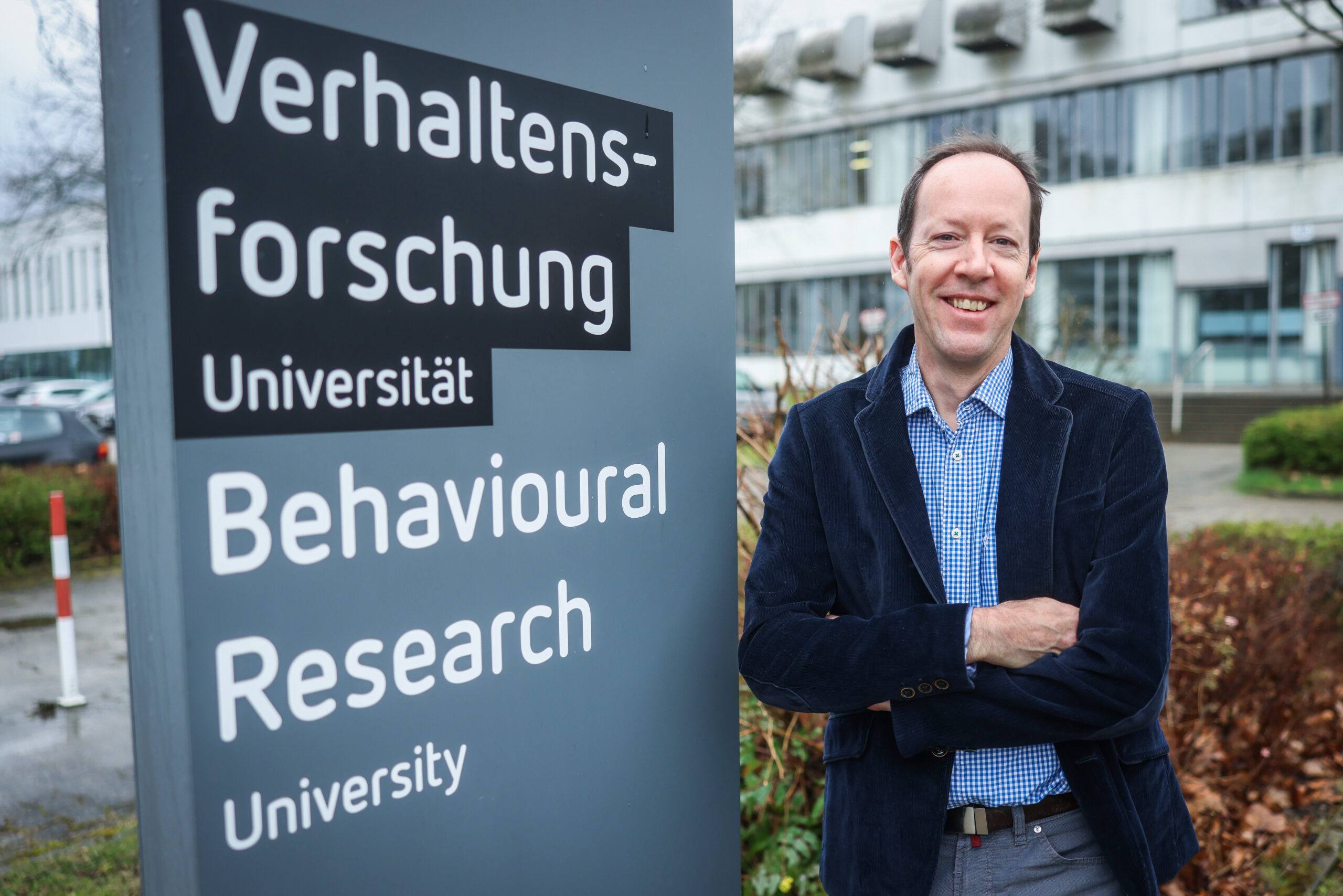 Professor Joseph Hoffman neben dem Schild der Verhaltensforschung an der Universität Bielefeld.
