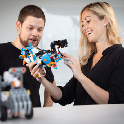 Zwei Personen betrachten und interagieren mit einem Robotik-Modell.