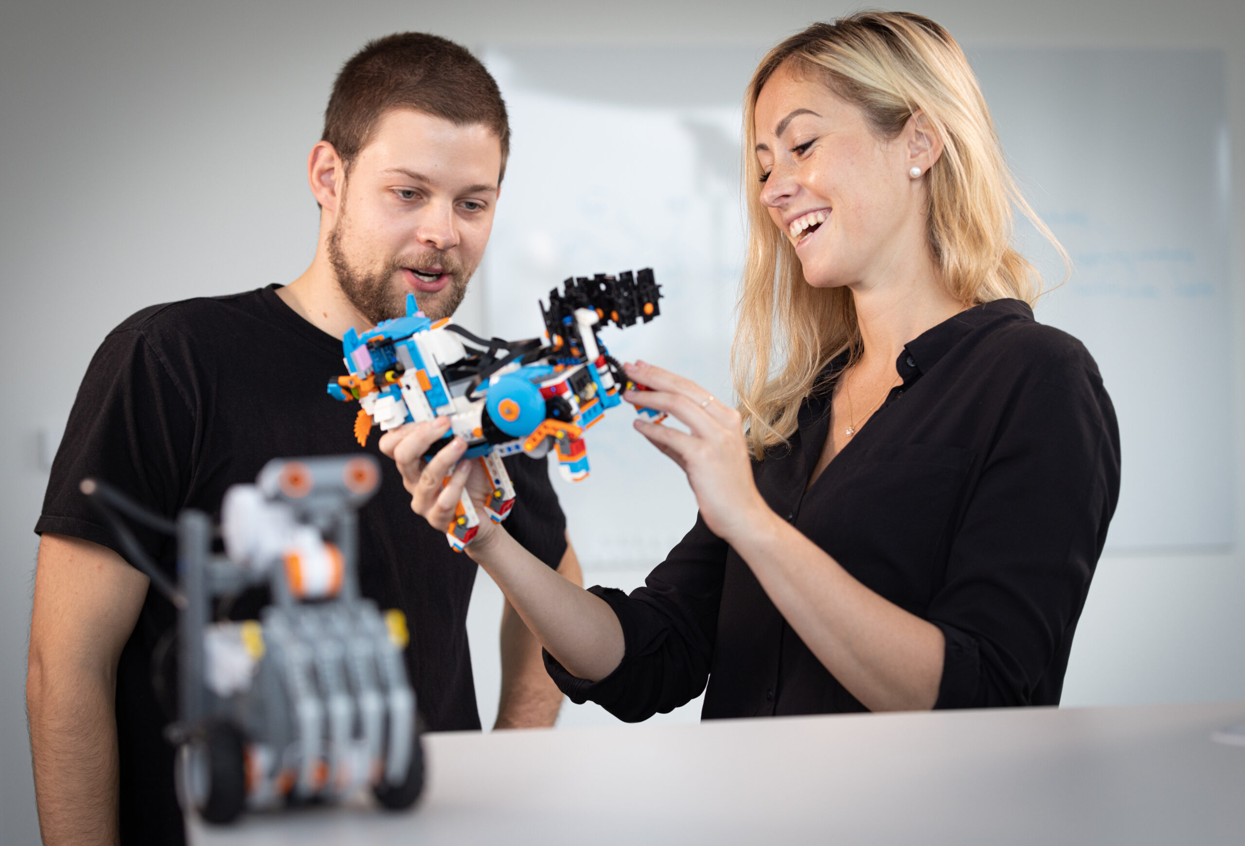 Zwei Personen betrachten und interagieren mit einem Robotik-Modell.