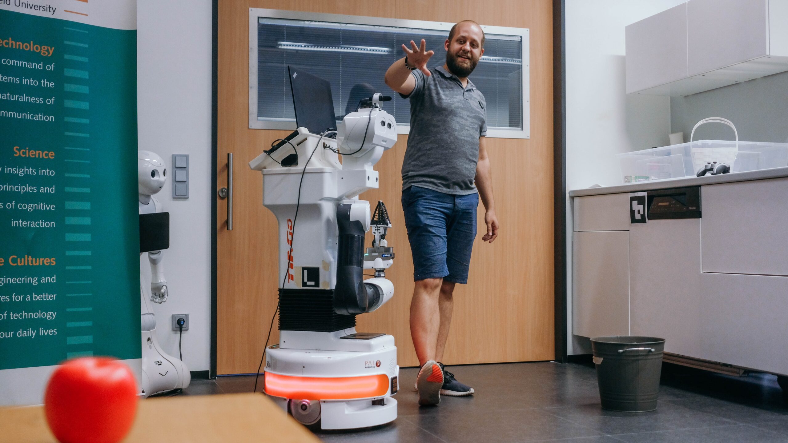 Ein Mann steht neben dem Serviceroboter im Labor
