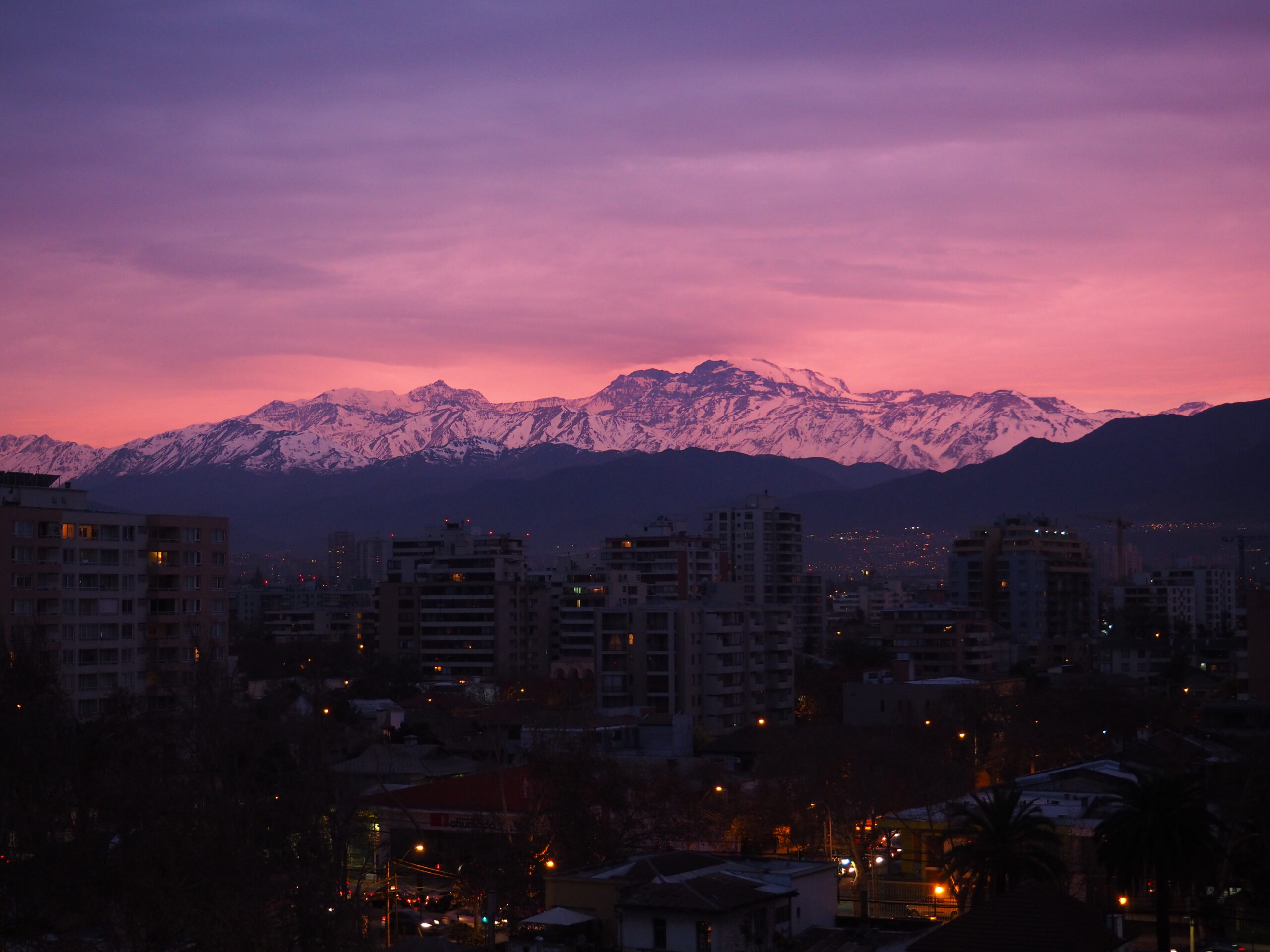 A twilight photo of a cityscape and mountains in the background.