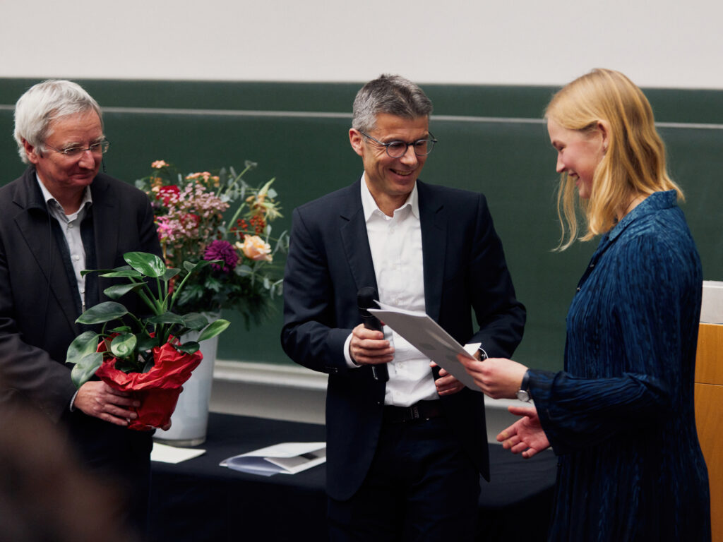 Johanna Weidelt (rechts) wird von Prof. Dr. Dario Anselmetti (mittig) und Dekan Prof. Dr. Walter Pfeiffer (links) für ihre Abschlussarbeit in der Fakultät für Physik mit dem Nachhaltigkeitspreis ausgezeichnet.