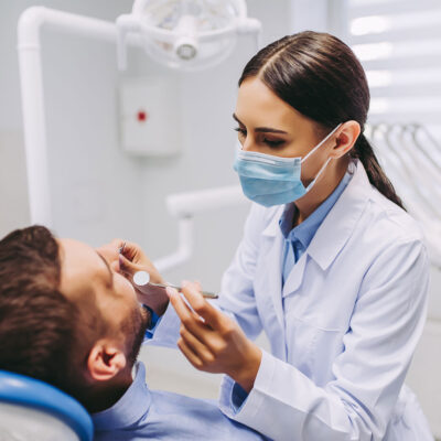 Eine Zahnärztin kontrolliert die Zahngesundheit eines Patienten.