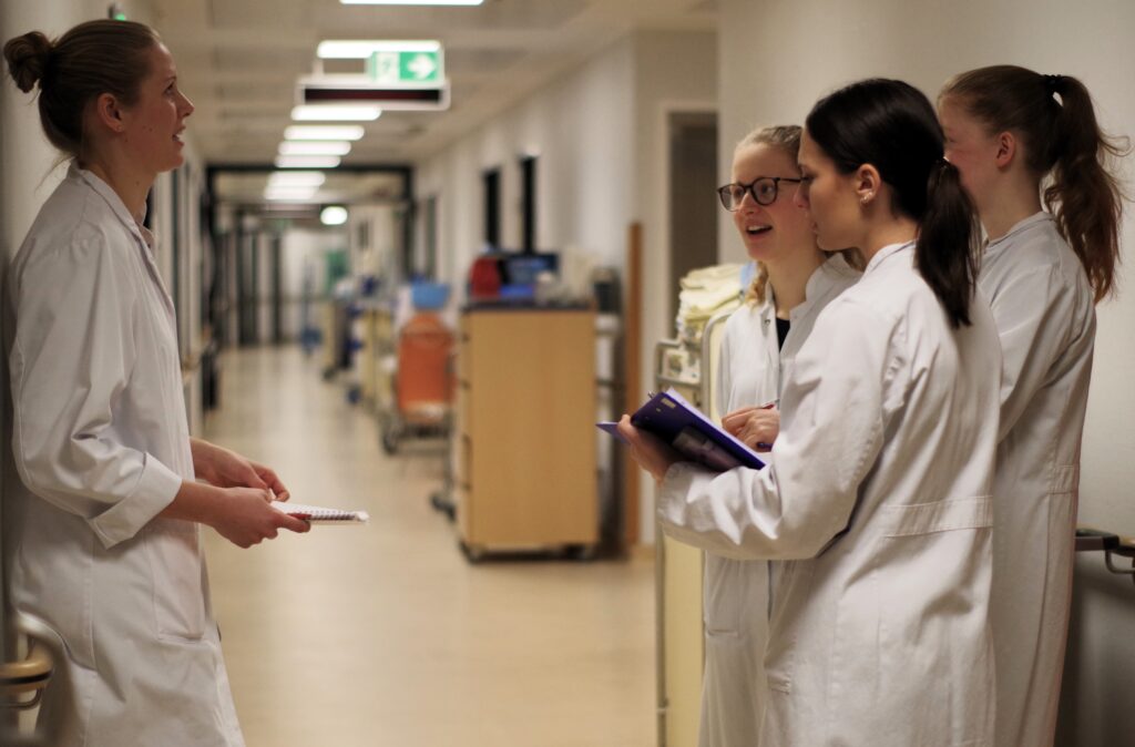 Studentinnen in weißen Kitteln auf einem Krankenhausflur