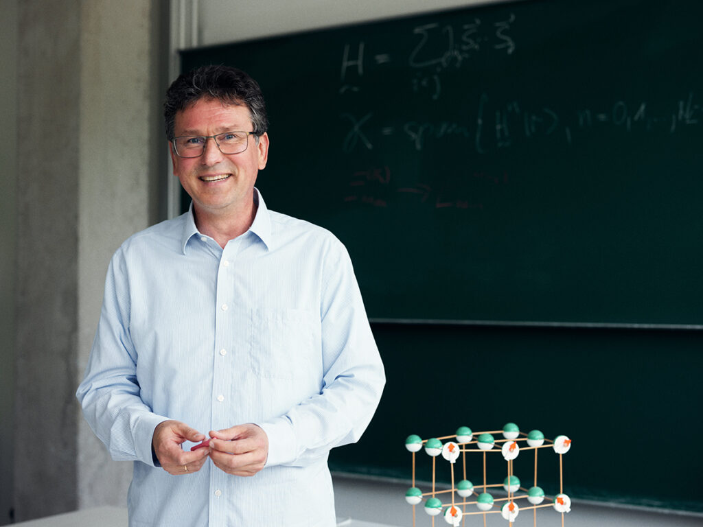 Prof. Dr. Jürgen Schnack vor einer Tafel, neben ihm ein Molekül-Modell