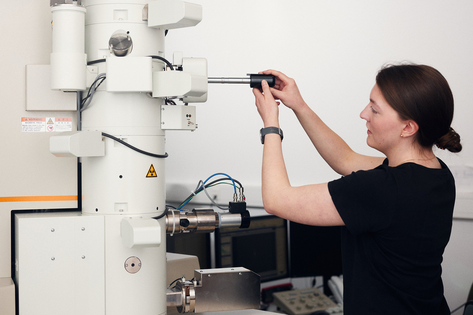 Young woman working with transmission electron microscope