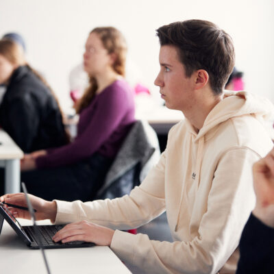 Studierender sitzt an einem Tisch. Vor ihm steht ein Tablet.