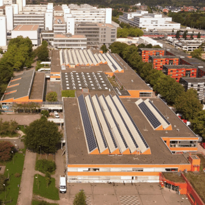 Luftaufnahme mit zwei Schulgebäuden im Vordergrund und dem Universitätshauptgebäude im Hintergrund