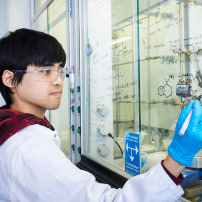 Satoshi Horino writing a chemical formula in the lab.