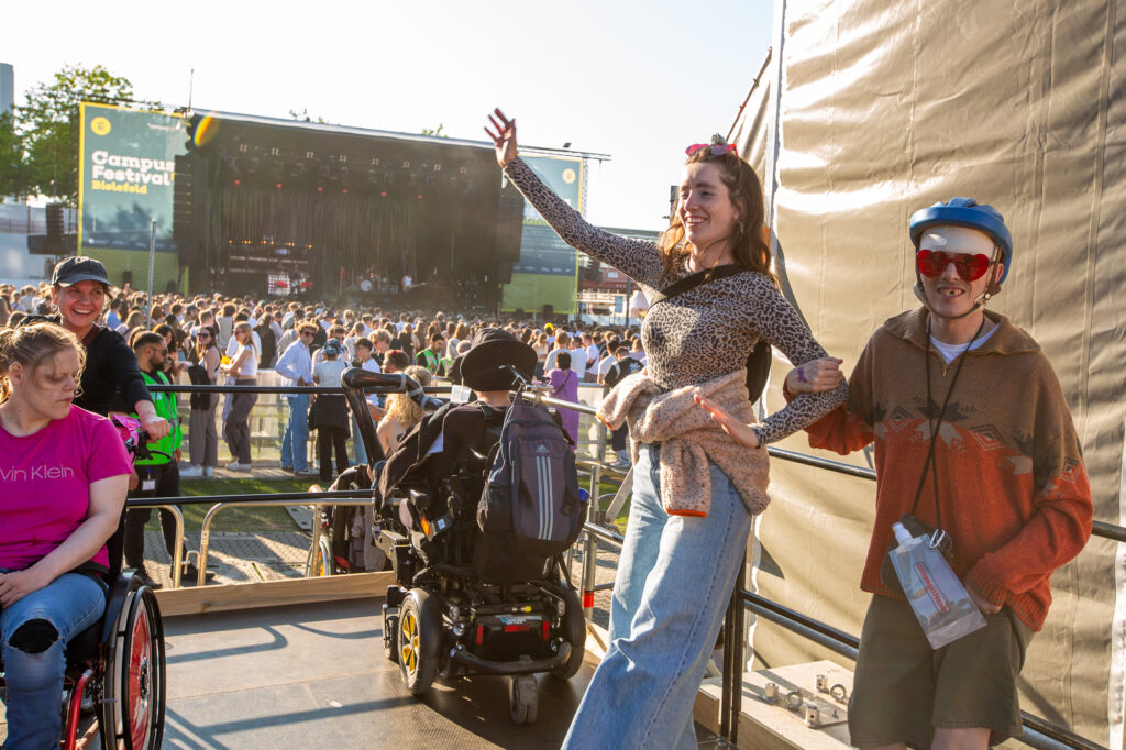 Tanzende Menschen auf der Rollstuhlfahrer*innentribüne
