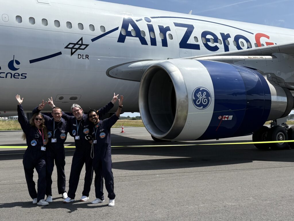 Eine weibliche und drei männliche Forscher*innen in Funktionsanzügen stehen vor einem Flugzeug.