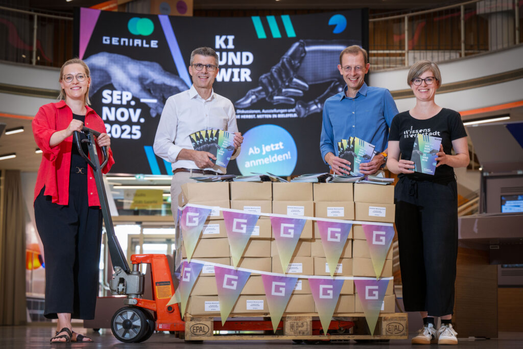 Gesa Fischer (Wissenswerkstadt), Prof. Dr. Dario Anselmetti (Universität Bielefeld), Prof. Dr. Ulrich Schäfermeier (Hochschule Bielefeld) und Maria Munzert (Wissenswerkstadt) mit den frisch gedruckten Programmheften für die GENIALE 2025.