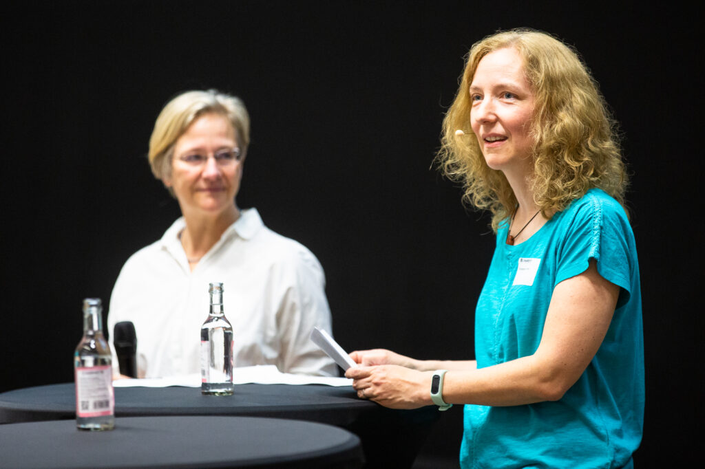 Rektorin Prof’in Dr. Angelika Epple (li.) und Prorektorin Prof’in Dr. Christiane Fuchs stehen hinter einem Tisch