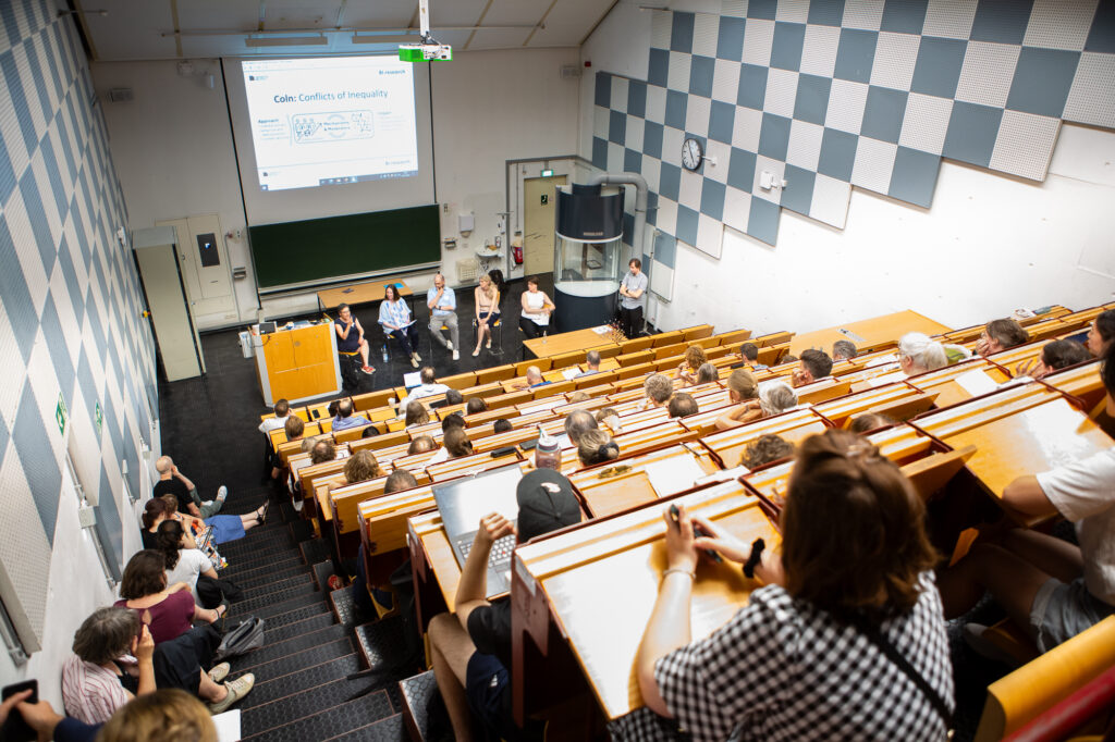 Leute sind in einem Vorlesungsraum gesetzt und hören zu.