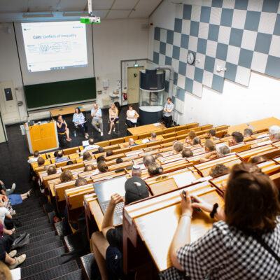 Leute sind in einem Vorlesungsraum gesetzt und hören zu.