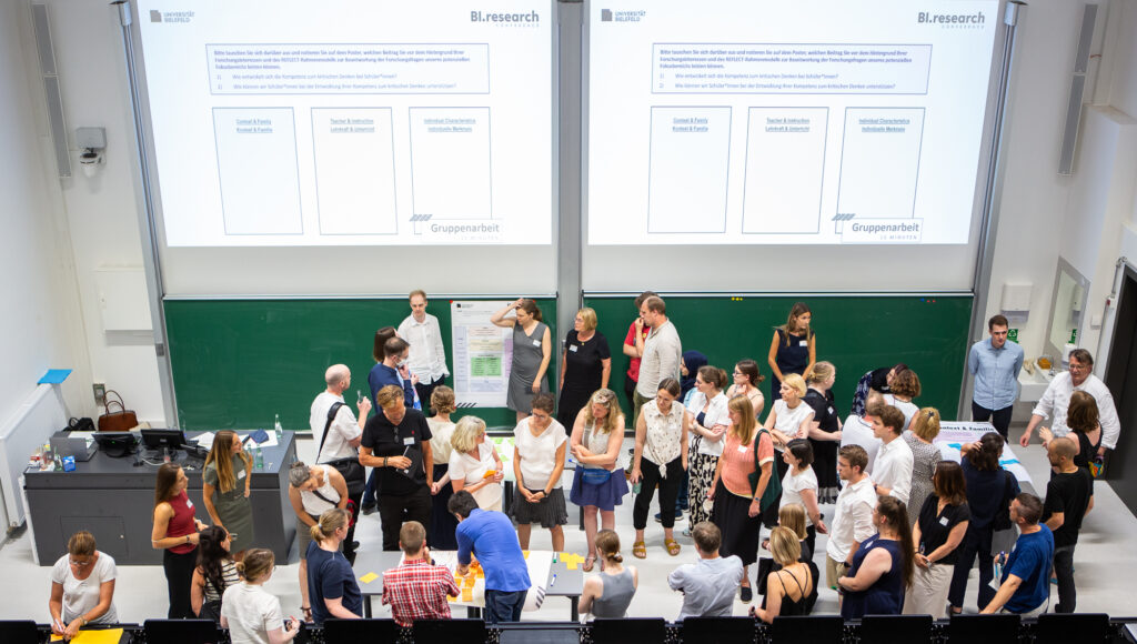 Publikum hat aktives Engagment und stehen alle im Hörsal vor dem Tafel und sprechen miteinander