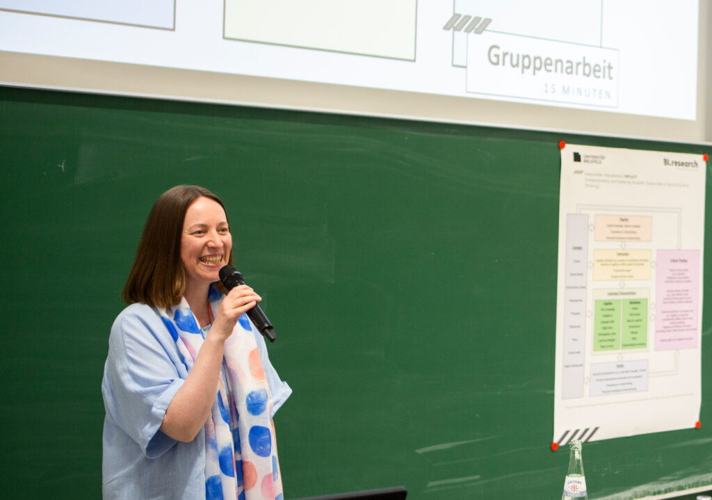 Professorin Dr. Kirsten Berthold mit Mikrofon, im Hintergrund eine Kreidetafel