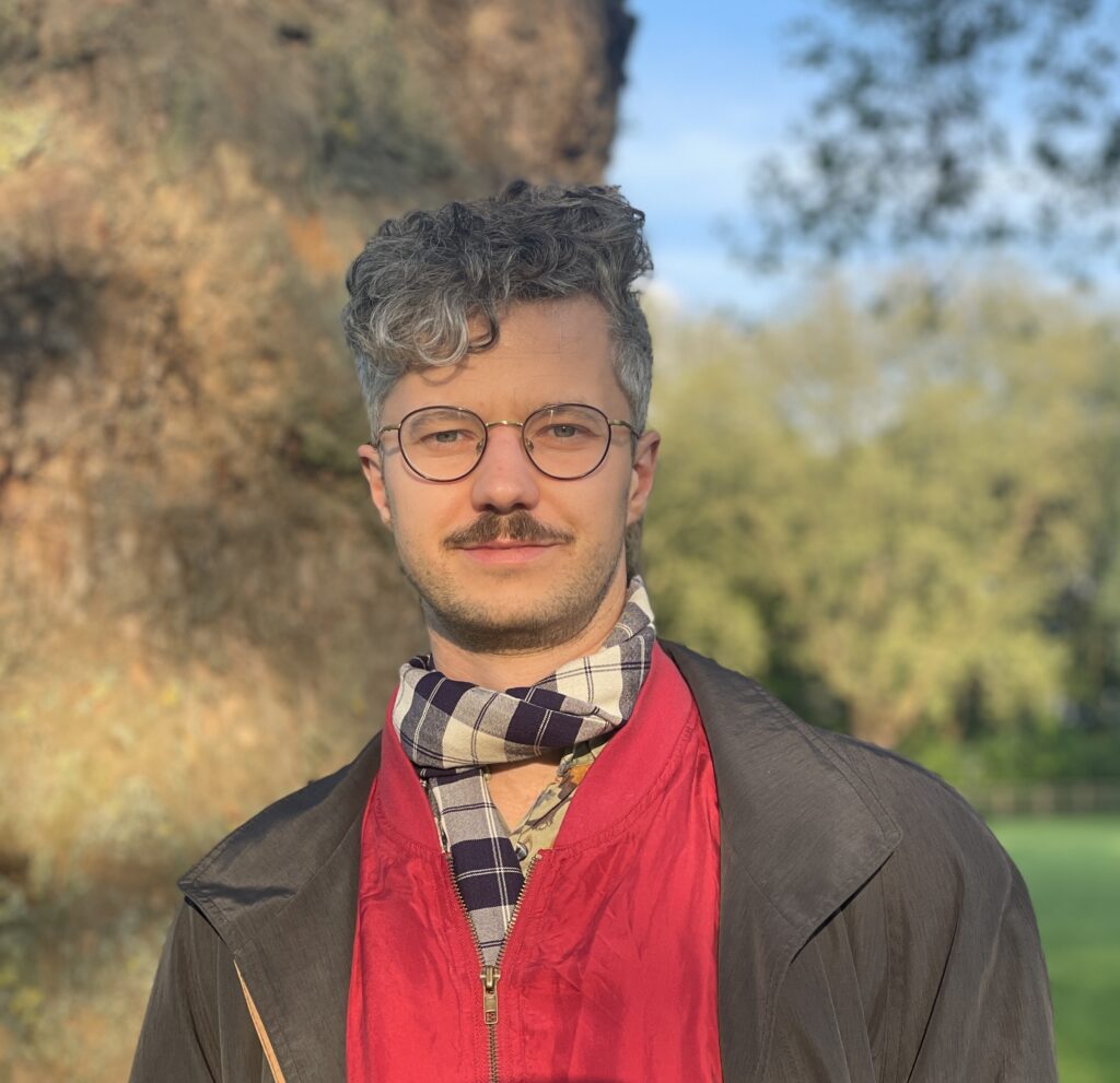 Mann mit Brille vor einem Baum