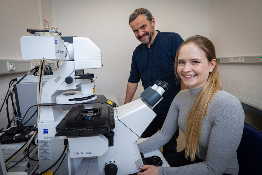 Zwei Personen mit einem großen Mikroskop.