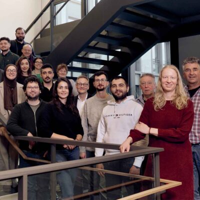 Eine Gruppe von PhD-Studierenden und Professor*innen auf einer Treppe.