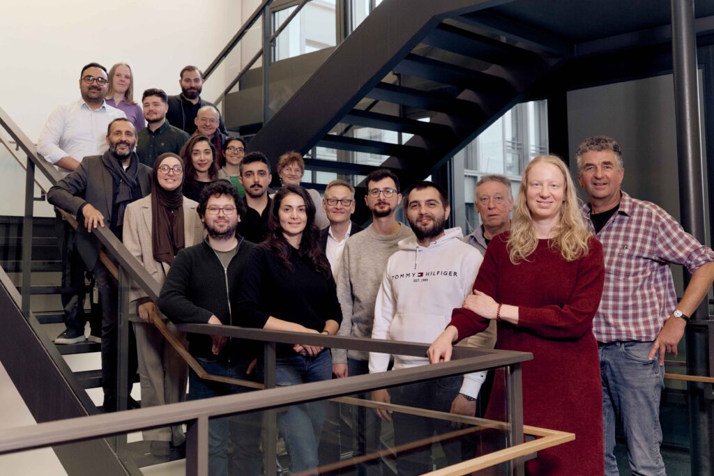 Eine Gruppe von PhD-Studierenden und Professor*innen auf einer Treppe.