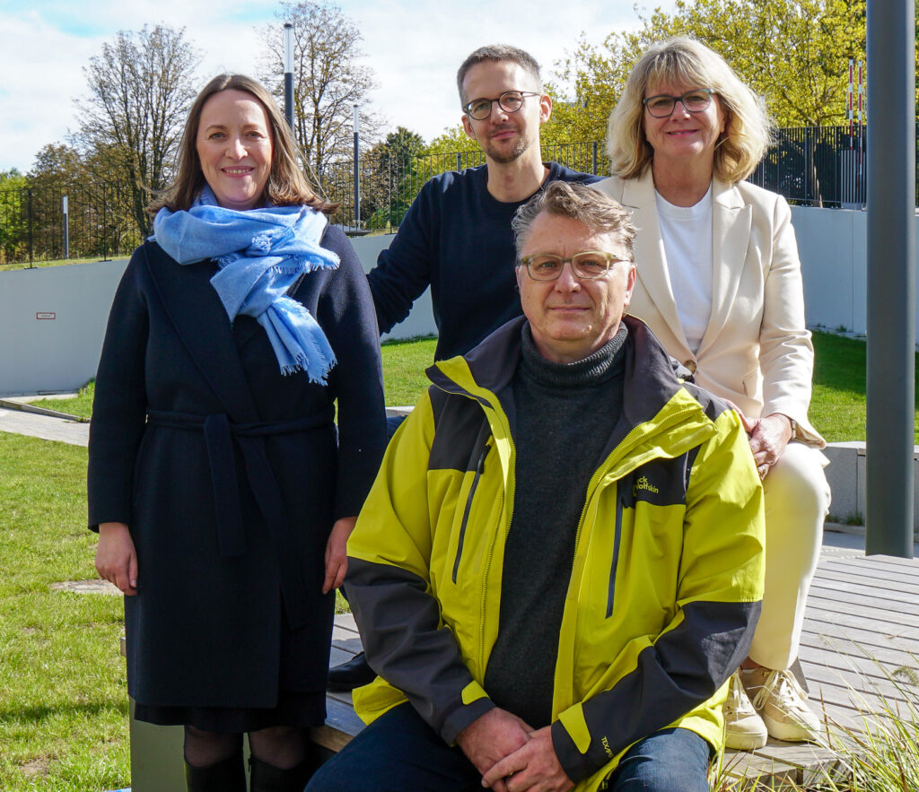 Outdoor shot of the four people with trees and lawn in the background