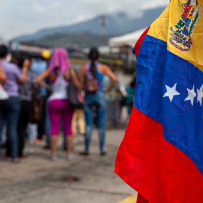 Unrecognizable women with their backs to the Venezuelan flag