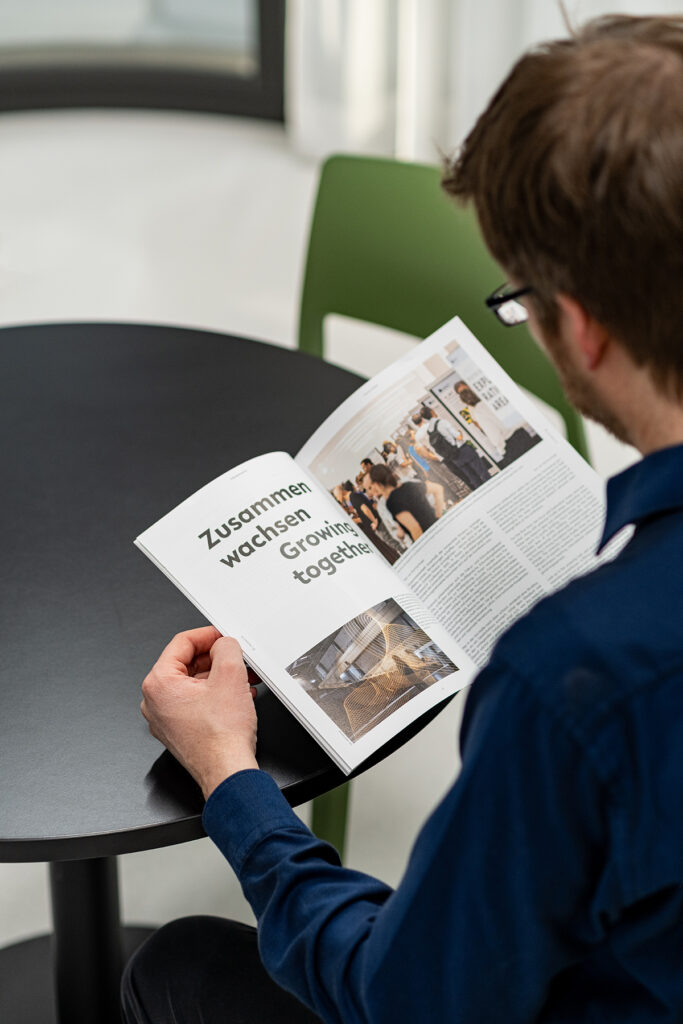 Mann blättert in Printmagazin, auffällige Überschrift im Magazin: Zusammen wachsen