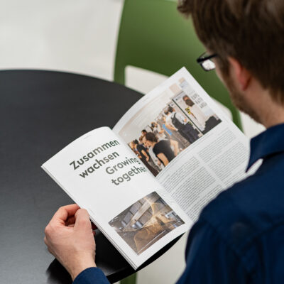 Mann blättert in Printmagazin, auffällige Überschrift im Magazin: Zusammen wachsen