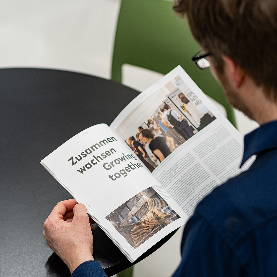 Man leafing through a print magazine, eye-catching headline in the magazine: Growing together
