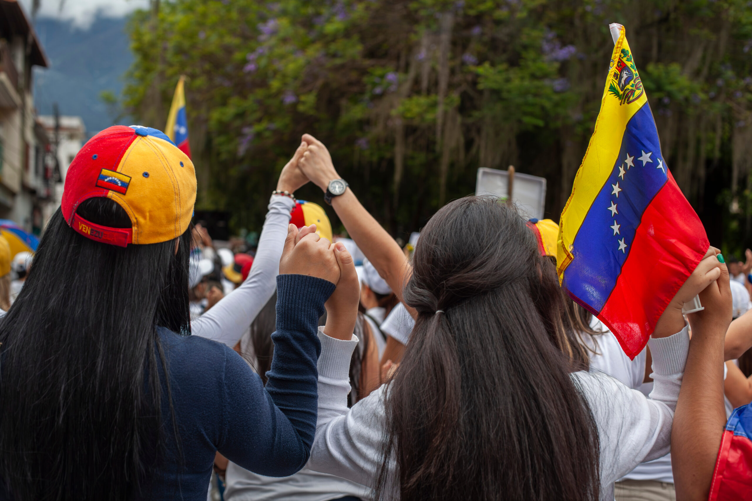 Venezuelan flags. Women's hands intertwined in prayer for a free Venezuela.