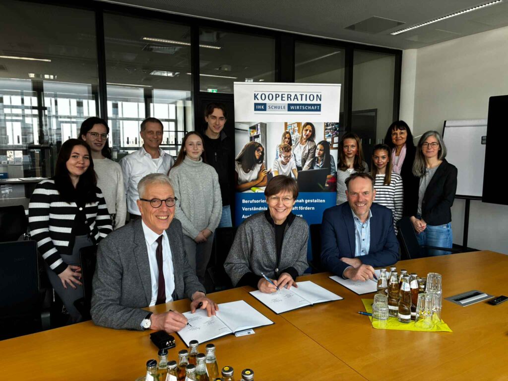 Dr. Stephan Becker, Kanzler und Leiter der Verwaltung der Universität, IHK-Geschäftsführerin Ute Horstkötter-Starke und Ansgar Leder, Schulleiter der Gertrud-Bäumer-Realschule (vorne von links) unterzeichnen im Beisein von Schüler*innen sowie weiteren Kooperationspartner*innen die Vereinbarung.