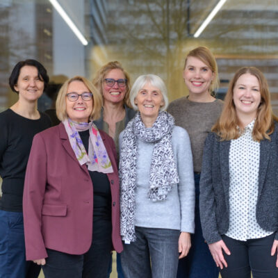 Gruppenfoto, Personen stehen außen vor einer großen Fensterscheibe