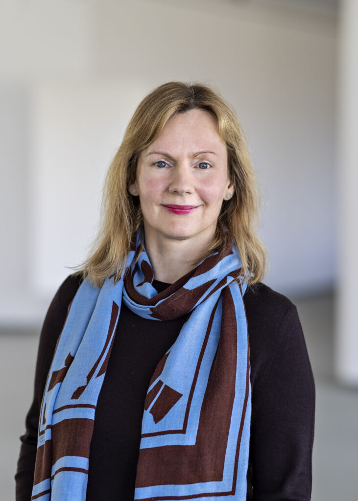 Bild einer blonden Frau mit blau-braunem Schal