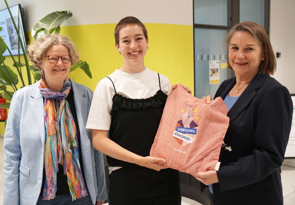 Als kleine Aufmerksamkeit des DAAD haben Karin Kruse (l.) und Heike Brandl (r.) aus dem International Office der Universität Bielefeld eine Erasmus+-Tasche mit verschiedenen Kleinigkeiten an Studentin Laura Terjung (Mitte) übergeben.