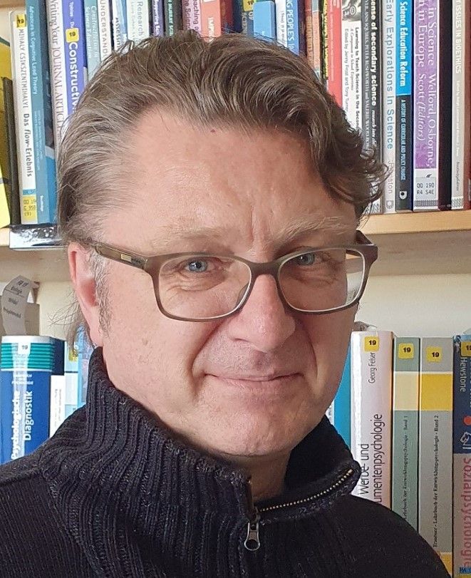 Mann mit Brille vor einem Bücherregal.