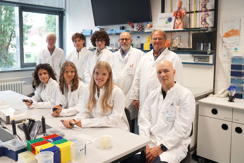 Gruppenfoto der Schüler*innen und Organisatoren der 13. CeBiTec-Schüler*innen-Akademie im Labor des Centrums für Biotechnologie. Von links nach rechts, hintere Reihe: Prof. Dr. Norbert Grotjohann (teutolab-biotechnologie), Albert Prokopets, Abdulkareem Mafoud (Schüler), Prof. Dr. Volker F. Wendisch (CeBiTec) und Rainer Menze (Bezirksregierung Detmold). Vordere Reihe: Angelina Aytan, Lisa Junghänel, Marlene Mand (Schülerinnen) und Prof. Dr. Tilo Grosser (Medizinische Fakultät).