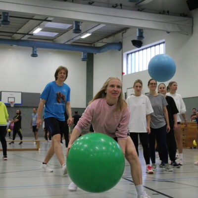 Sportlehrer spielen mit goßen Gymnastikbällen.